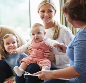 Woman holding an infant with young girl sitting next to her - Parent Child Interaction Therapy (PCIT)