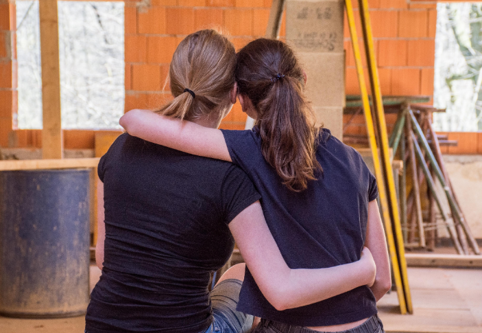 Two women hugging and leaning on each other